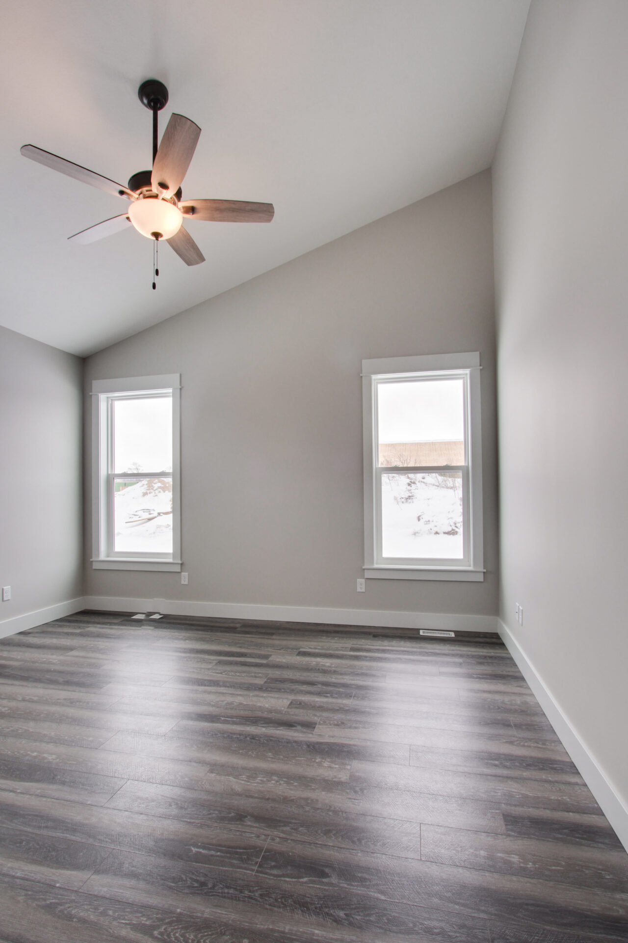 Light colour empty bedroom in a new construction house with a ceiling fan