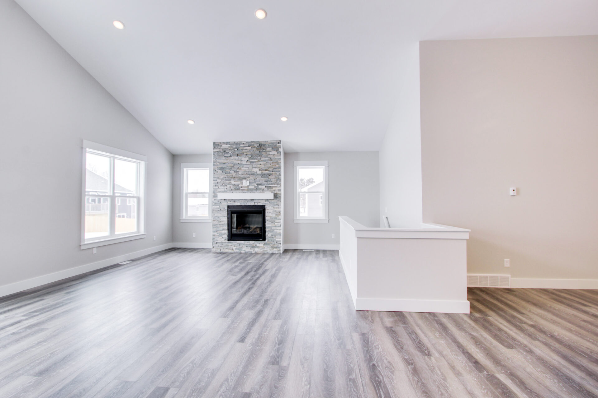 Empty living room with a fireplace, white walls and hardwood floor
