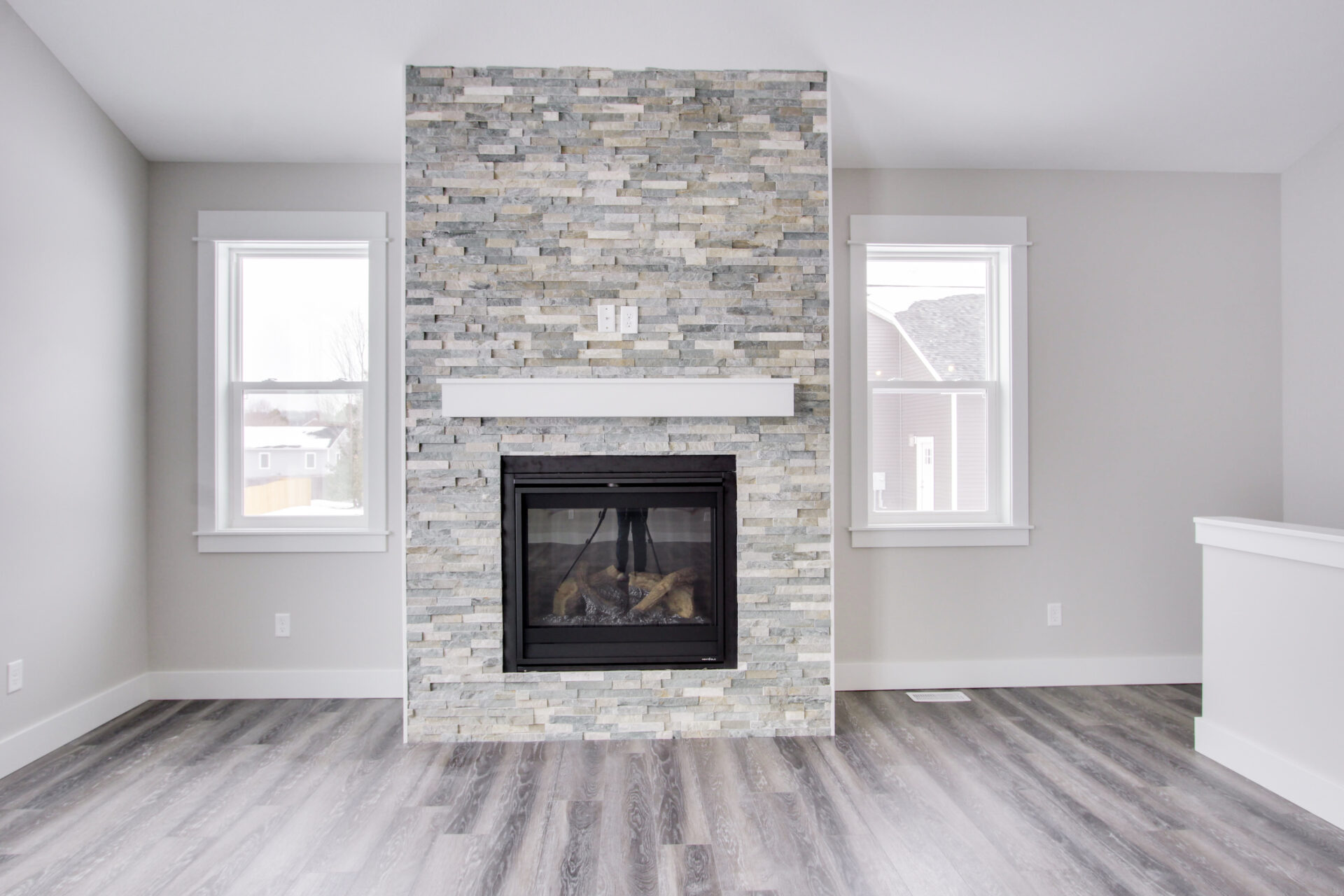 Empty living room with a fireplace, white walls and hardwood floor