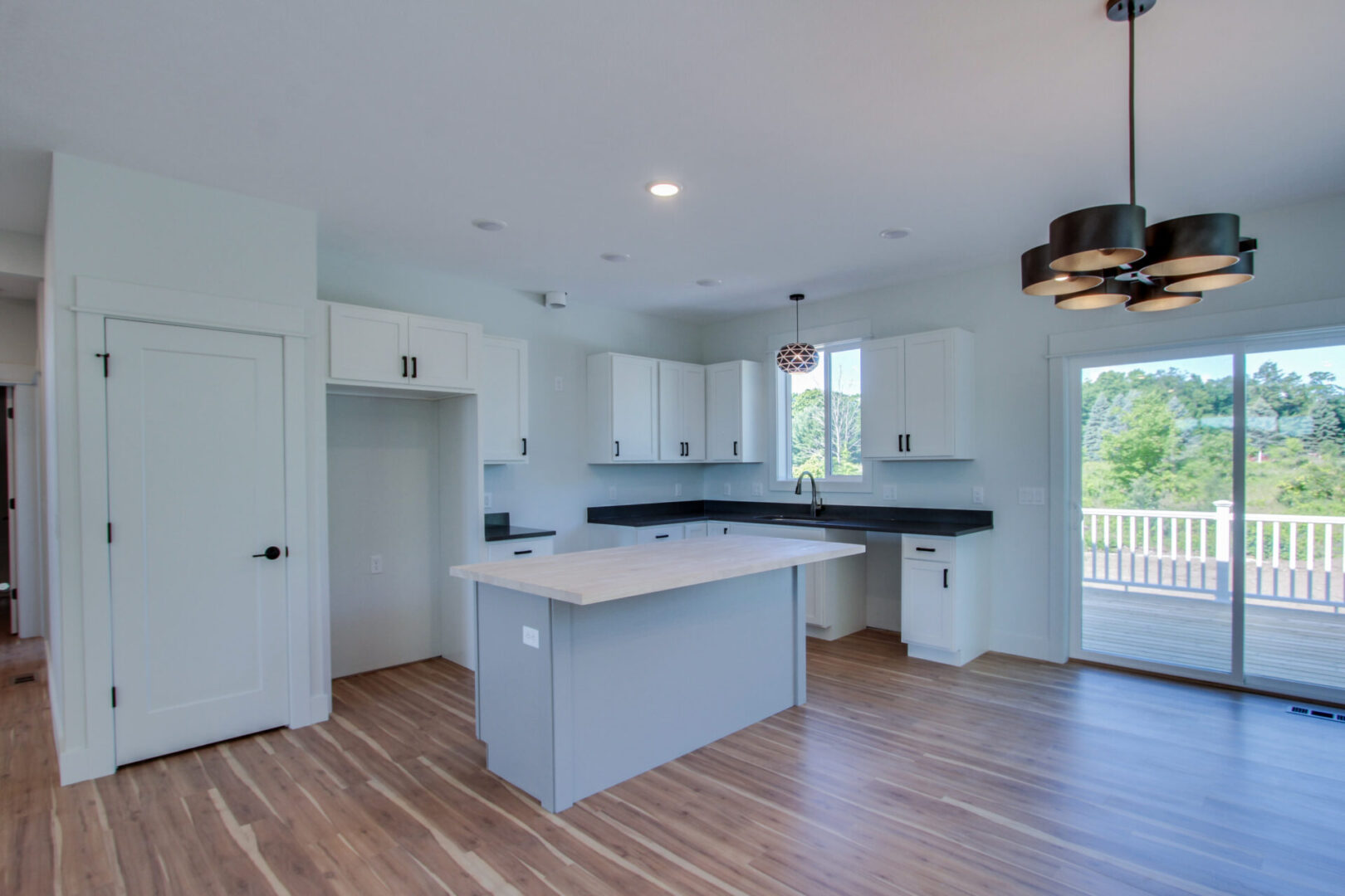 A kitchen with white sink, cabinets, countertops, and more